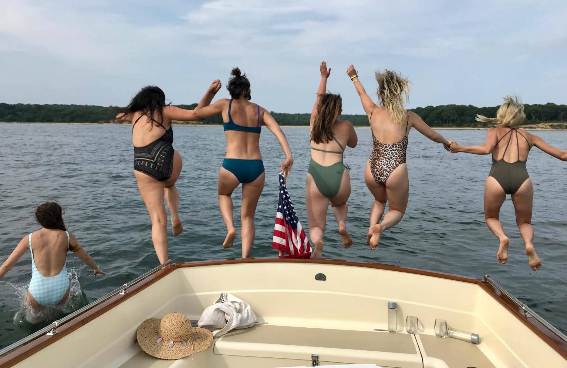 Women jumping off the back of a boat during a private charter near the Hamptons.